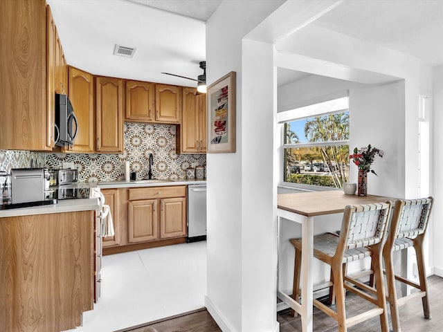 kitchen featuring ceiling fan, dishwasher, sink, tasteful backsplash, and range