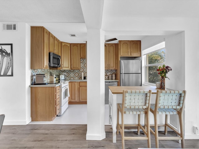 kitchen featuring decorative backsplash, stainless steel appliances, and light hardwood / wood-style flooring