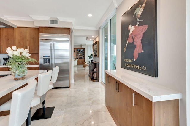 kitchen with ornamental molding, stainless steel built in refrigerator, and wall chimney exhaust hood