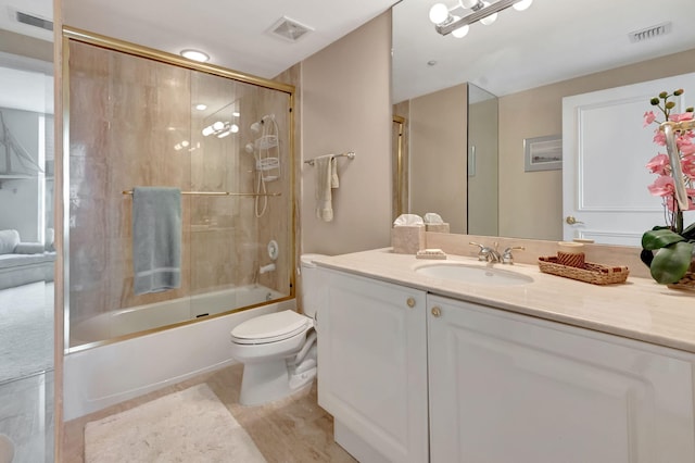 full bathroom with combined bath / shower with glass door, hardwood / wood-style flooring, vanity, and toilet