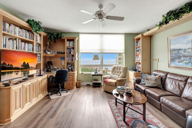 office with ceiling fan, light wood-type flooring, a textured ceiling, and built in desk