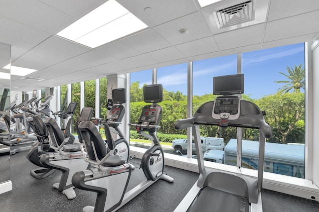 exercise room with a wall of windows and a drop ceiling