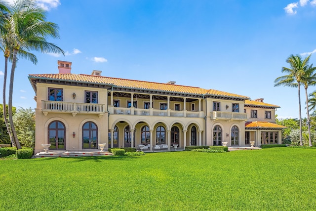 back of property with a lawn and a balcony