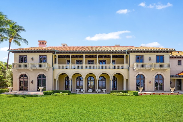 back of property featuring a lawn and a balcony