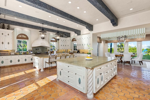 kitchen with pendant lighting, backsplash, a spacious island, a kitchen bar, and white cabinetry