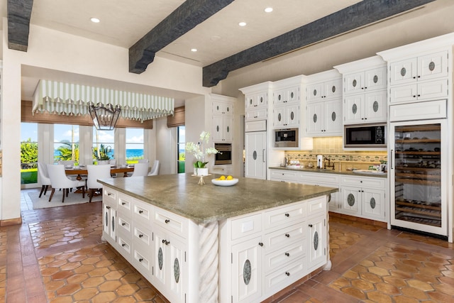 kitchen with backsplash, stainless steel oven, a kitchen island, black microwave, and wine cooler