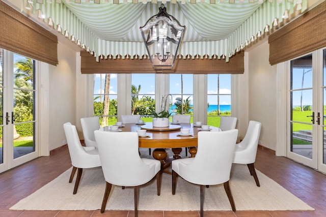 dining area featuring hardwood / wood-style floors, a chandelier, a water view, and french doors