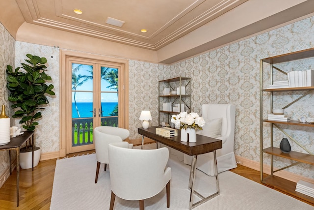 home office with wood-type flooring, a water view, a tray ceiling, and crown molding