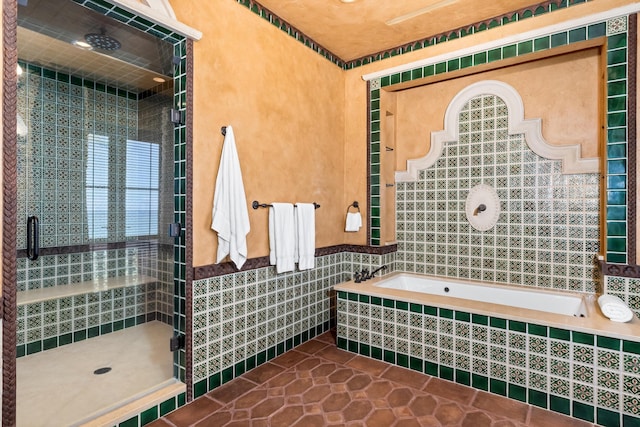 bathroom with tile patterned flooring, independent shower and bath, and tile walls