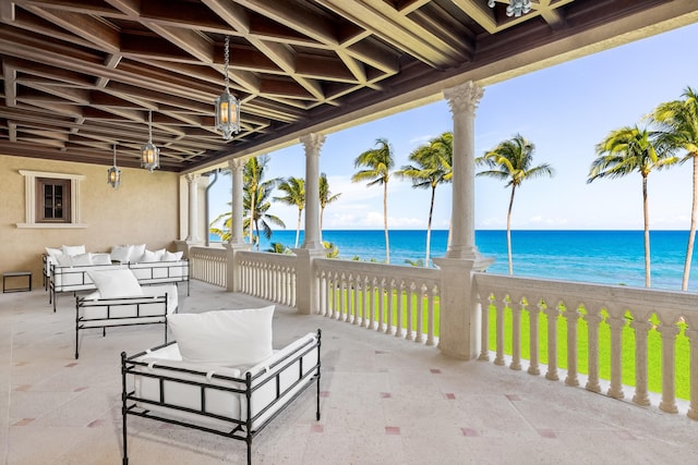 view of patio / terrace featuring an outdoor living space, a water view, and a beach view