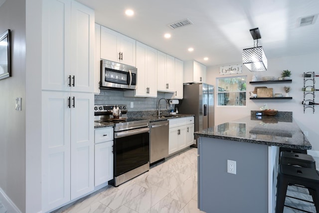 kitchen featuring a breakfast bar, stainless steel appliances, white cabinetry, and backsplash