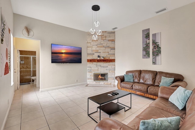 living room featuring a stone fireplace and light tile patterned floors