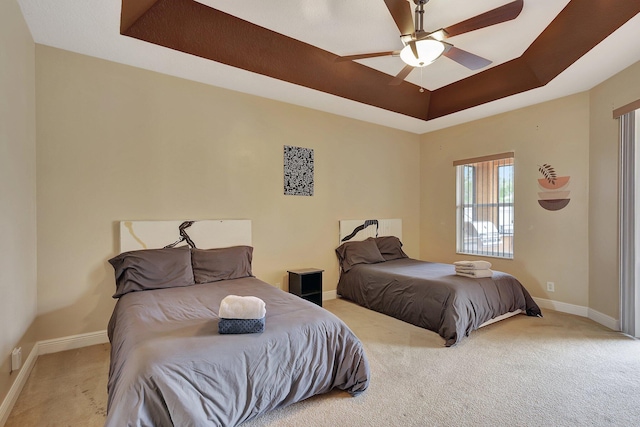 bedroom featuring a raised ceiling, light carpet, and ceiling fan