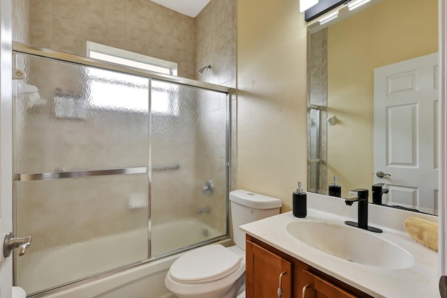 full bathroom with bath / shower combo with glass door, vanity, and toilet