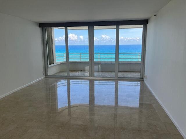 unfurnished room featuring tile patterned flooring, a water view, and plenty of natural light