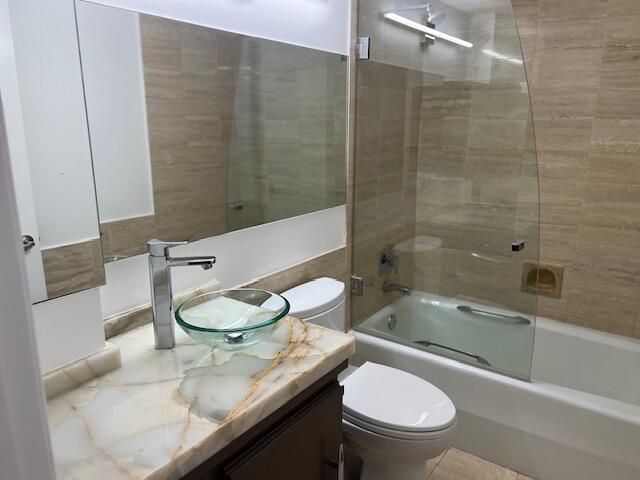 full bathroom featuring vanity, toilet, and shower / bath combination with glass door