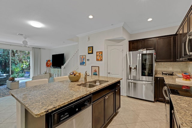 kitchen featuring dark brown cabinets, stainless steel appliances, sink, ceiling fan, and a center island with sink