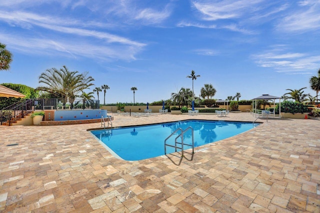 community pool with a patio area, fence, and a gazebo