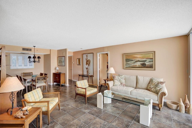 living room with a chandelier, a textured ceiling, visible vents, and baseboards