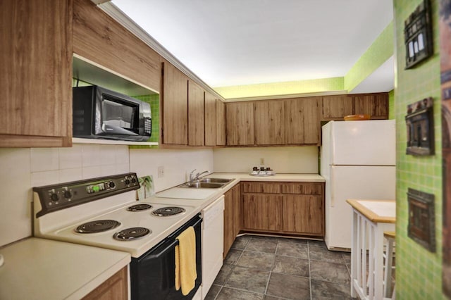 kitchen with a sink, brown cabinetry, white appliances, and light countertops