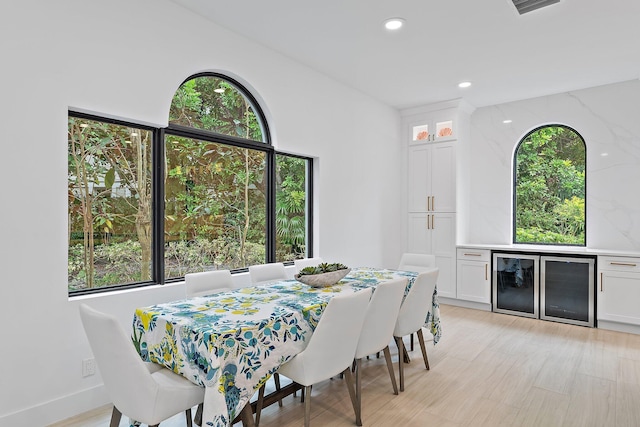 dining area featuring light wood-type flooring, recessed lighting, and beverage cooler