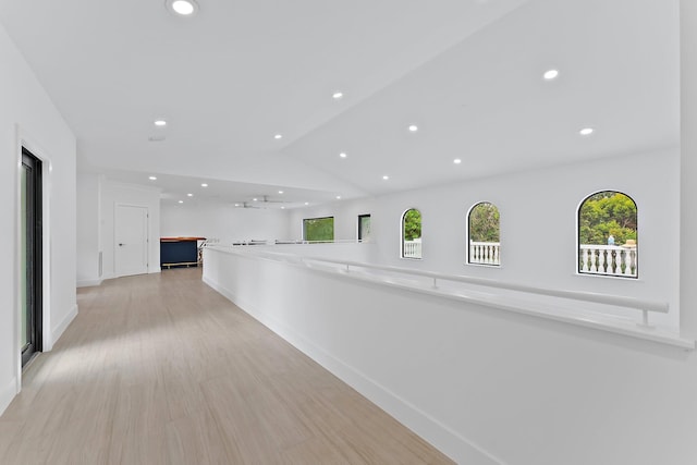 hallway featuring baseboards, vaulted ceiling, light wood-type flooring, and recessed lighting