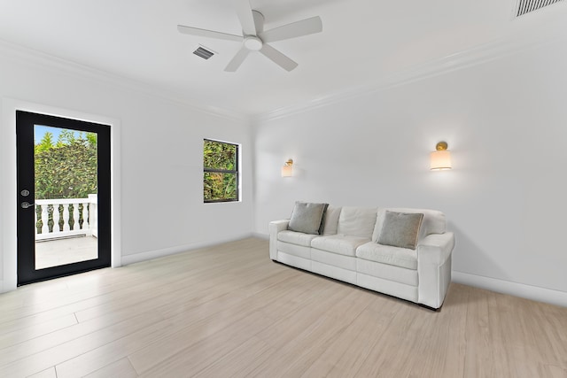 living area with light wood-style floors, visible vents, and crown molding