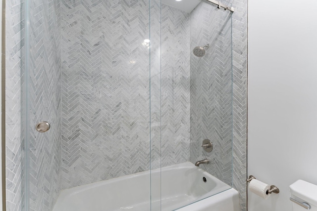 bathroom with tiled shower / bath combo and toilet