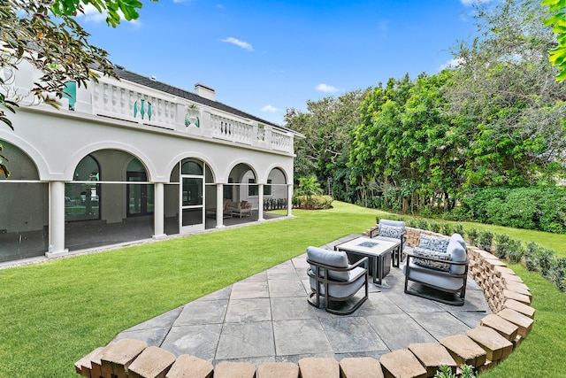 exterior space with a yard, a balcony, an outdoor living space with a fire pit, and a patio