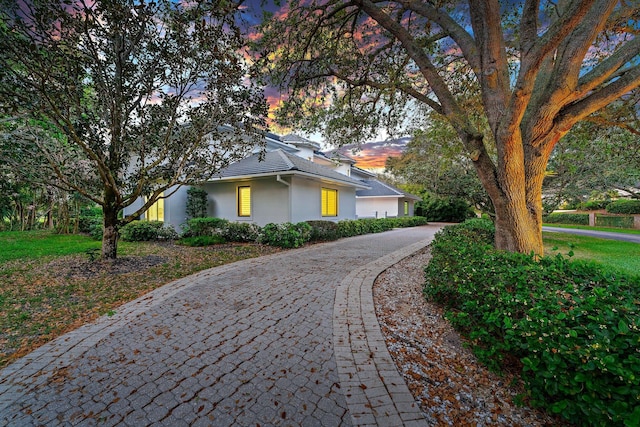 property exterior at dusk featuring decorative driveway and stucco siding