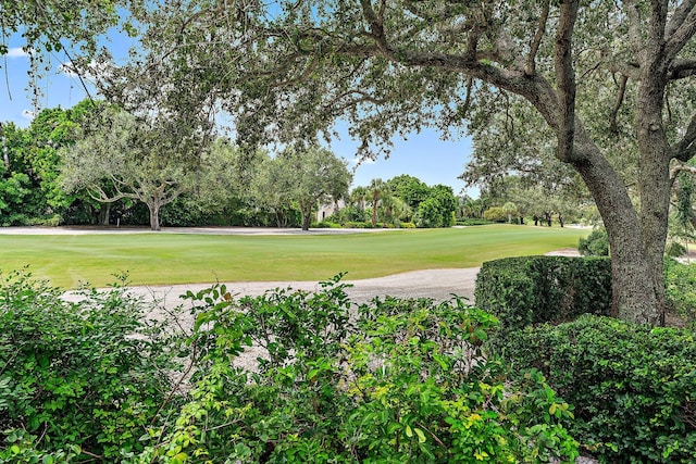 surrounding community with view of golf course and a lawn