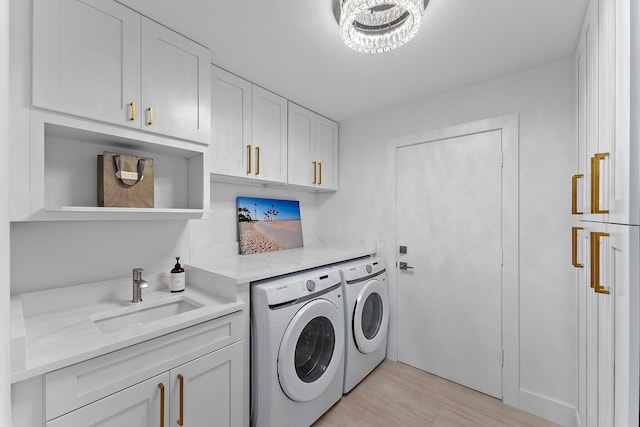 laundry area with light hardwood / wood-style flooring, cabinets, sink, and washing machine and clothes dryer