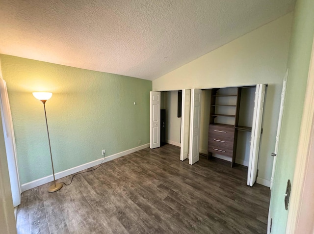 unfurnished bedroom featuring a textured ceiling, two closets, dark hardwood / wood-style floors, and vaulted ceiling