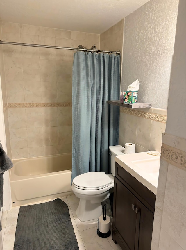 full bathroom featuring shower / bath combination with curtain, vanity, toilet, tile walls, and tile patterned flooring