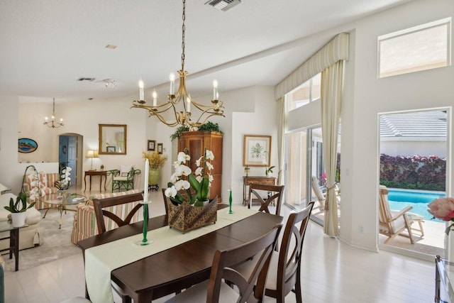 dining space with light hardwood / wood-style flooring, a chandelier, and vaulted ceiling