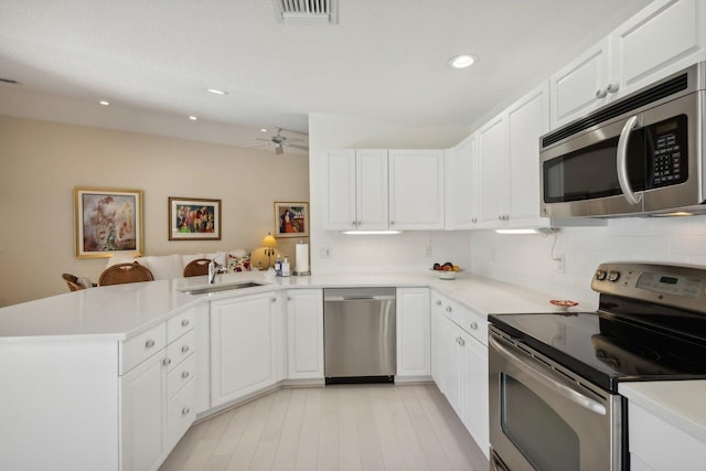 kitchen featuring white cabinets, stainless steel appliances, kitchen peninsula, ceiling fan, and decorative backsplash