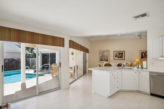 kitchen with stainless steel dishwasher, kitchen peninsula, ceiling fan, light wood-type flooring, and white cabinets