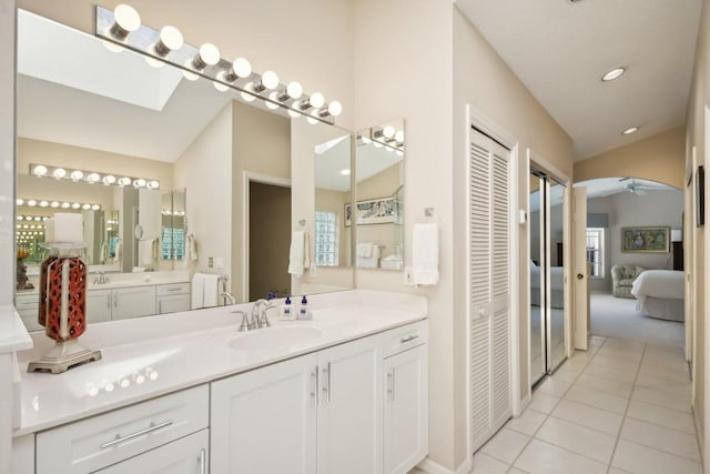 bathroom with vanity, ceiling fan, lofted ceiling with skylight, and tile patterned floors