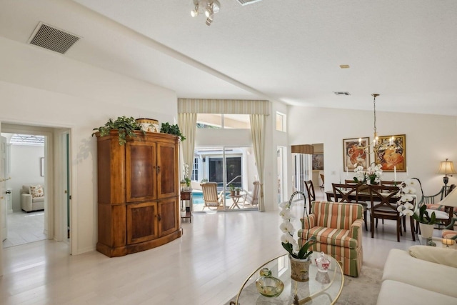 living room featuring vaulted ceiling, an inviting chandelier, and light hardwood / wood-style floors