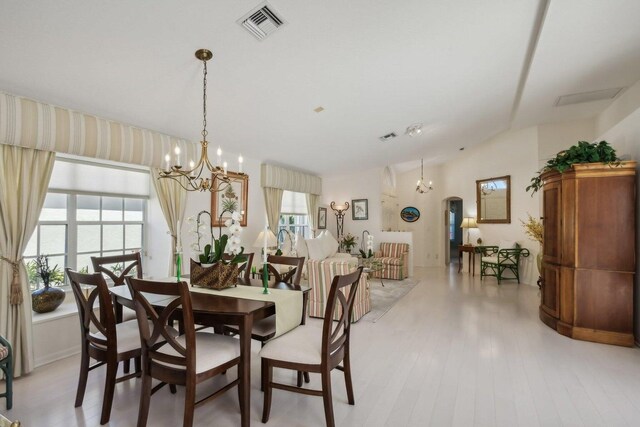 dining room featuring light hardwood / wood-style floors, a notable chandelier, and vaulted ceiling