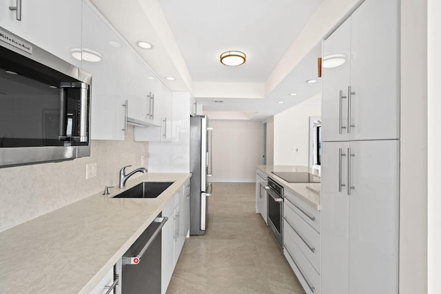 kitchen featuring a sink, appliances with stainless steel finishes, light countertops, and white cabinetry