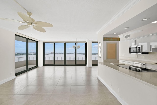 interior space with stainless steel microwave, visible vents, a wall of windows, ornamental molding, and white cabinetry