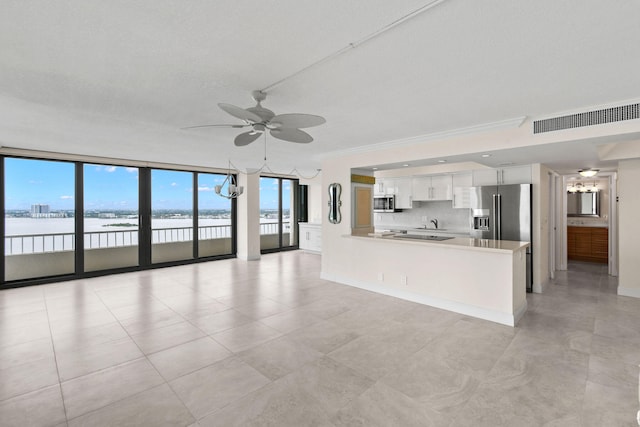 kitchen with white cabinets, a water view, appliances with stainless steel finishes, a wall of windows, and kitchen peninsula