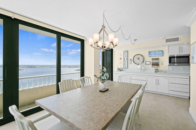 dining room with plenty of natural light, a water view, ornamental molding, and an inviting chandelier