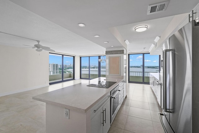 kitchen with baseboards, visible vents, light tile patterned flooring, stainless steel appliances, and floor to ceiling windows