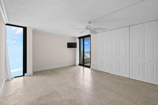 unfurnished room featuring crown molding, baseboards, ceiling fan, floor to ceiling windows, and a textured ceiling