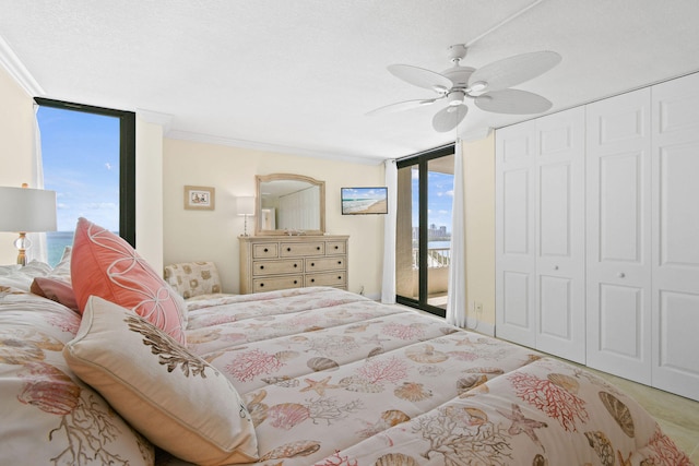 bedroom with a wall of windows, ornamental molding, a closet, a ceiling fan, and access to outside