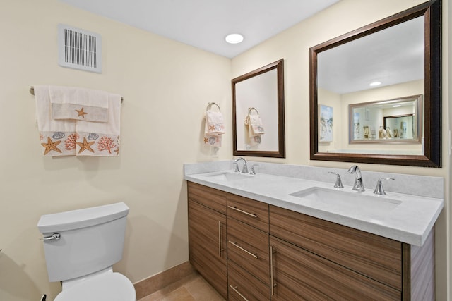 bathroom featuring a sink, visible vents, toilet, and double vanity