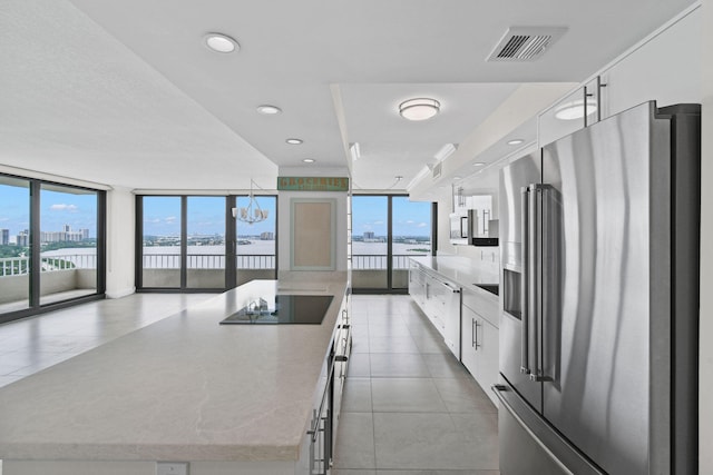 kitchen with white cabinets, high end refrigerator, a kitchen island, and a wall of windows