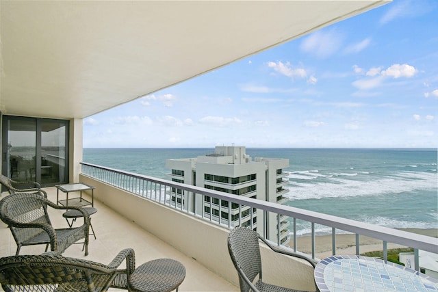 balcony featuring a view of the beach and a water view